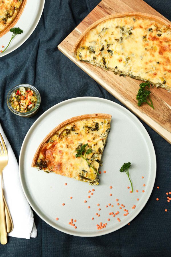 Teller mit vegetarischer Quiche, dekoriert mit frischen Kräutern und buntem Gemüse.