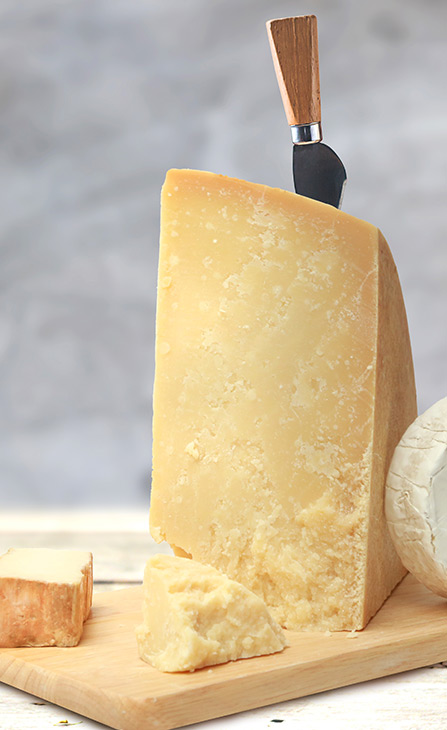 Holzbrett mit einem Stück Parmesan und einem Parmesanmesser, ideal für Käseliebhaber und Feinschmecker.