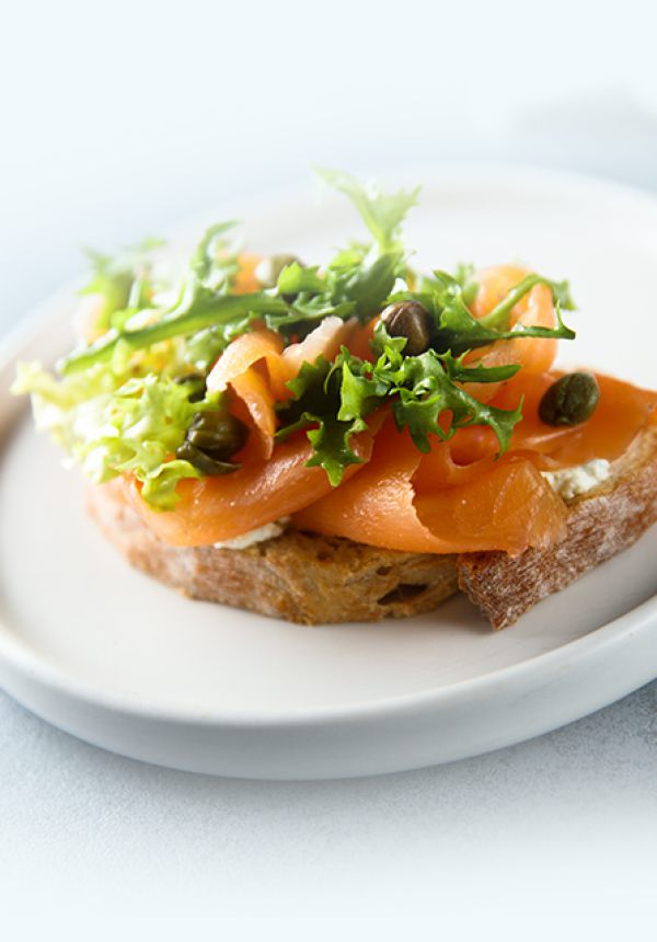 Fischbrötchen, belegt mit frischem Fisch und Salat, präsentiert auf einem weißenTeller