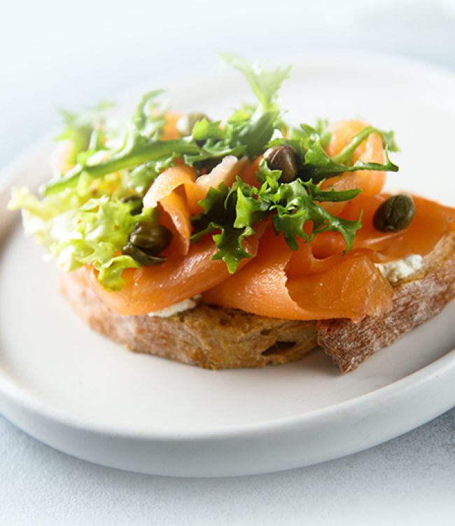 Fischbrötchen, belegt mit frischem Fisch und Salat, präsentiert auf einem weißenTeller