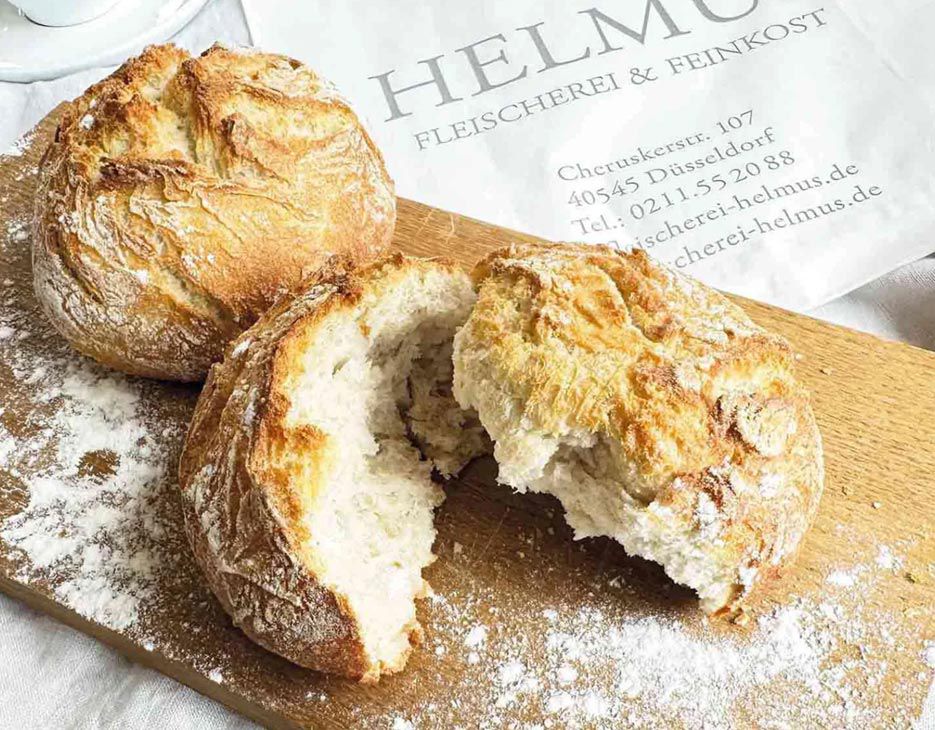 Eine Auswahl frischer Brötchen auf einem rustikalen Holzbrett, ideal für ein Frühstück.