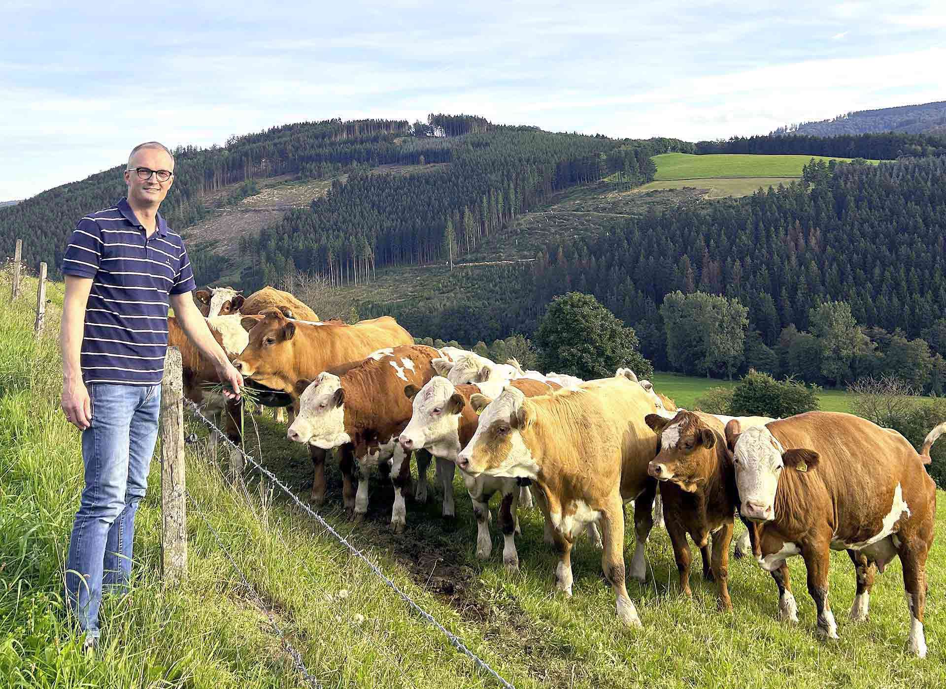 Stephan Helmus steht beim Weiderind am Zaun