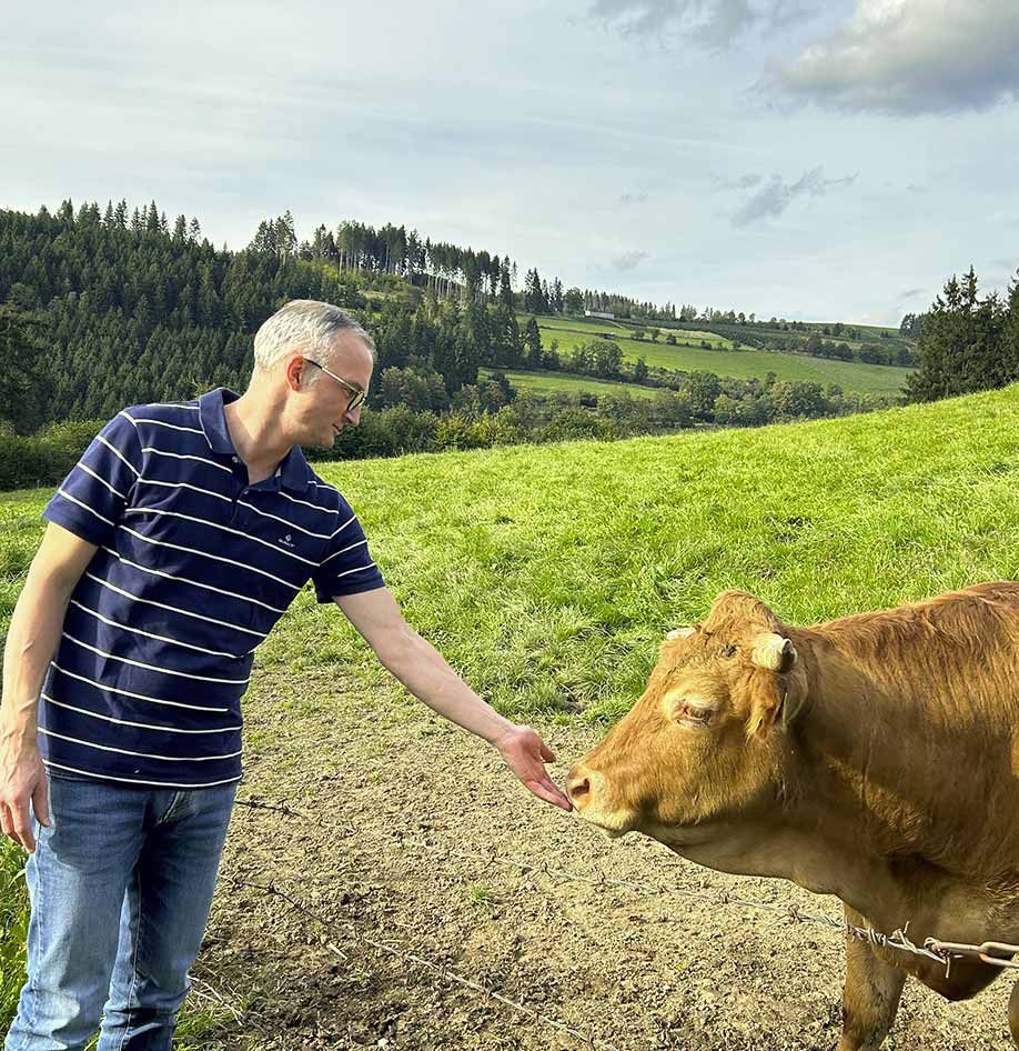 Stephan Helmus steht beim Weiderind am Zaun