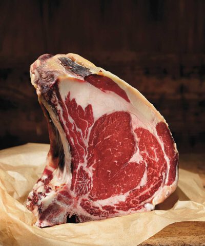 Nahaufnahme eines Steaks von vorne, das auf einem Holzbrett präsentiert wird. 