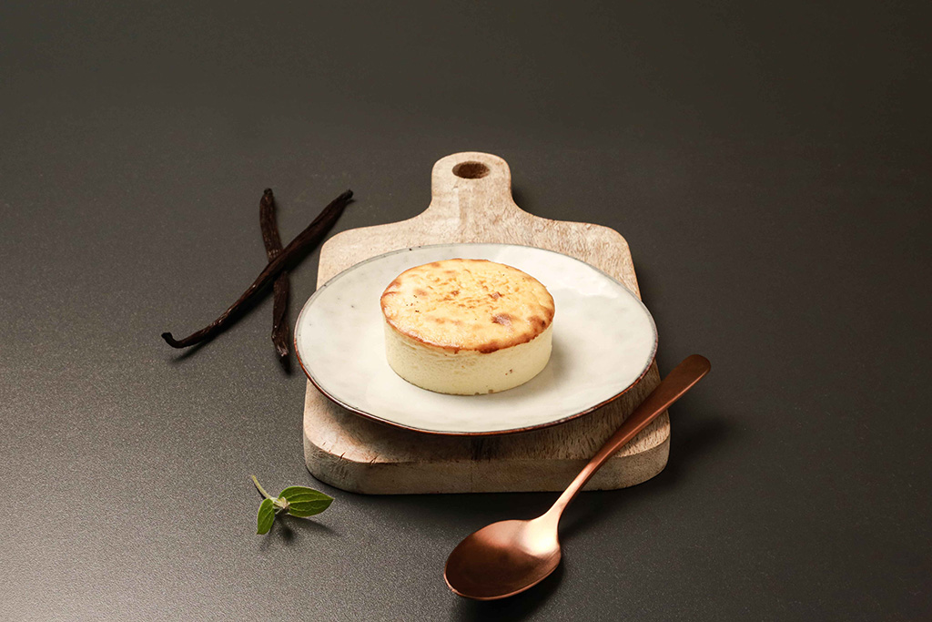 San Sebastian Cheesecake auf einem eleganten Teller, dekoriert mit Vaniliestangen.