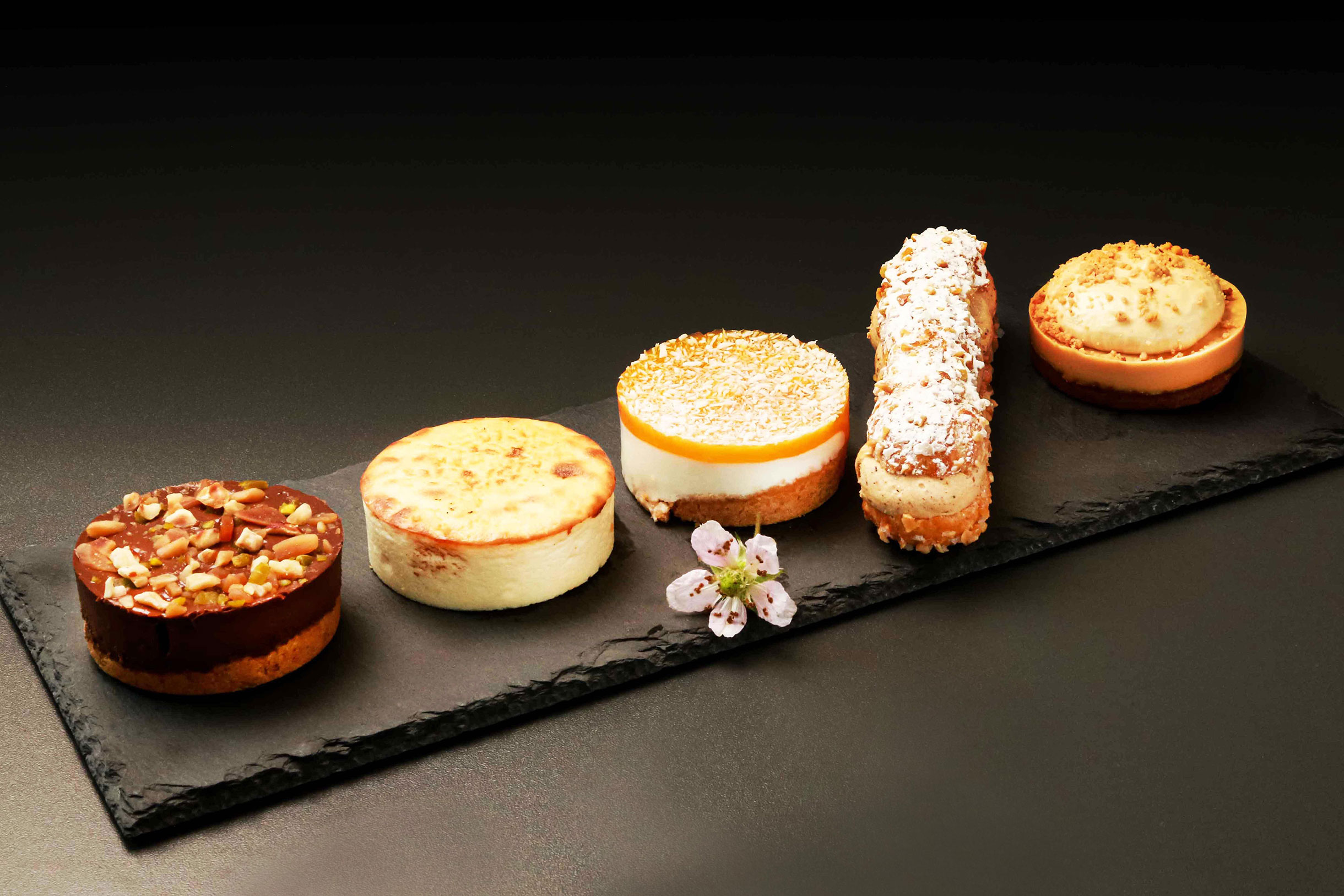 Auf einer Schieferplatte angerichtetes Patisserie-Gebäck, präsentiert in einer eleganten Anordnung.