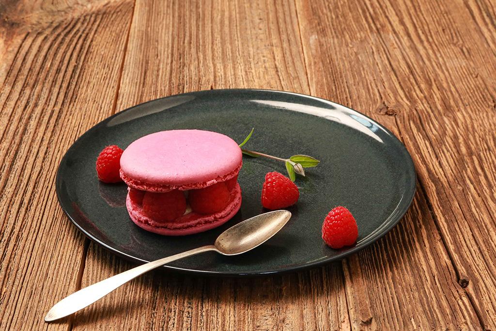 Sable-Macron-Himbeere auf einem Teller, dekoriert mit frischen Himbeeren.