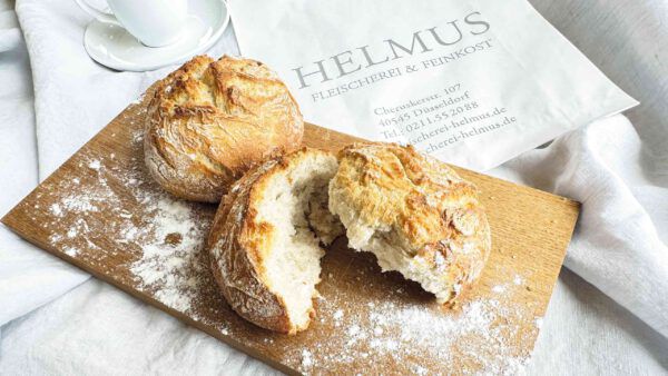 Frische Brötchen auf einem Holzbrett, appetitlich angeordnet und bereit zum Servieren.