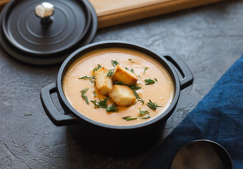 Eleganter Kochtopf mit Kürbissuppe und Croutons
